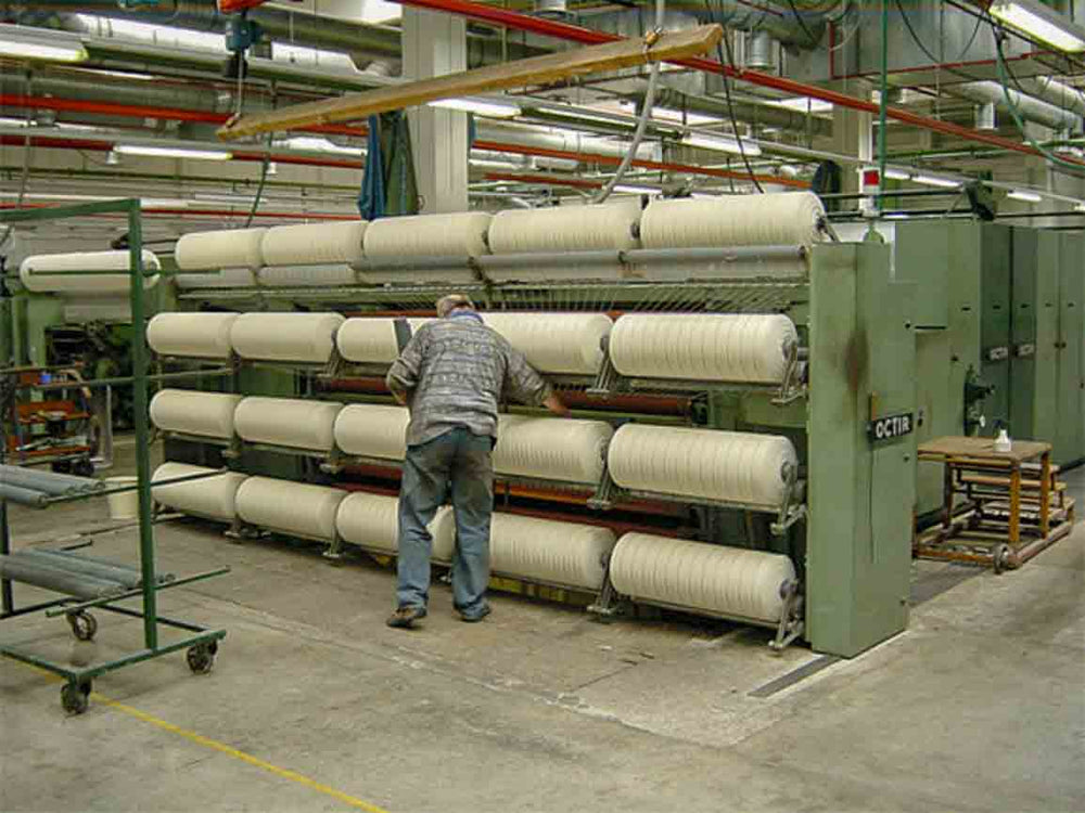 man tending to spun wool in tradional mill