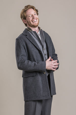 a side frontal view of a 30 year old man wearing a 100% virgin austrian loden wool coat over a loden wool vest and loden wool pants