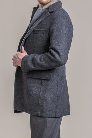 a side view of a 30 year old man wearing a 100% virgin austrian loden wool coat over a loden wool vest and loden wool pants
